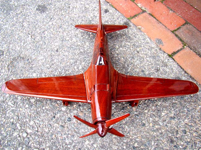 A beautiful carved mahogany depiction of a World War II fighter plane, possibly a Grumman Hellcat F6F
